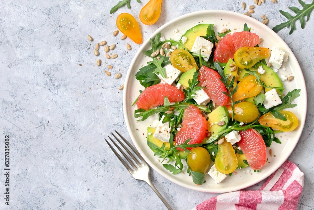 Avocado salad with grapefruits, tomato, feta cheese, arugula and sunflower seeds. Top view with copy space. Avocado salad with grapefruits, tomato, feta cheese, arugula and sunflower seeds. Top view with copy space.
