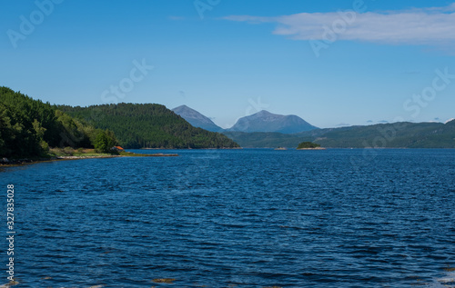 Beautiful landscape view cross a fjord or bay in Norway with clear blue sky and sunlight and mountains in the background. Ferry between Kanestraum - Halsa. July 2019 © Сергій Вовк