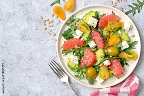 Avocado salad with grapefruits, tomato, feta cheese, arugula and sunflower seeds. Top view with copy space.