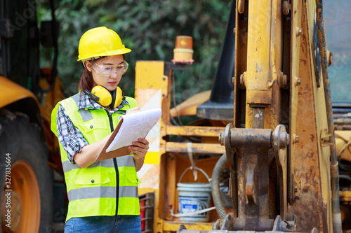 Asian female worker wear safety suits checking  of tracked excavator
