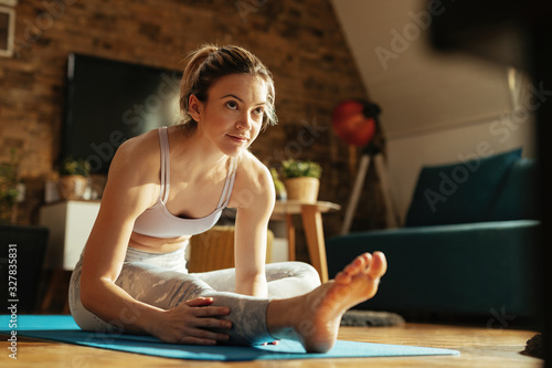Athletic woman stretching her legs while exercising at home.