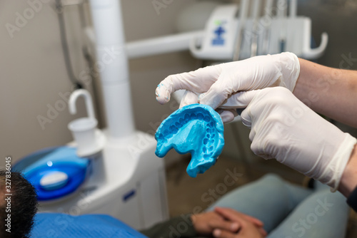 Dentist hands with latex gloves holding dental mold of the patient.