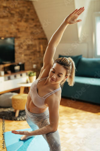 Young woman doing Yoga stretching exercises at home.