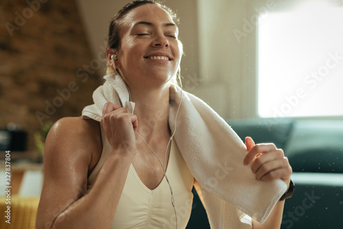 Sweaty athletic woman listening music over earphones at home. photo