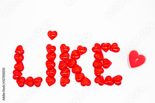 The word  like  is lined with red glass hearts on a white background  on the right - a candle in the shape of a heart. The concept of social networks  approval  support