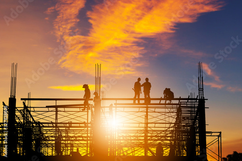Silhouette of Engineer and worker on building site, construction site with clipping path at sunset in evening time.
