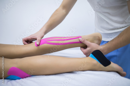 Manual, physio and kinesio therapy techniques performed by a male physiotherapist on a training plastic spine and a female patient leg