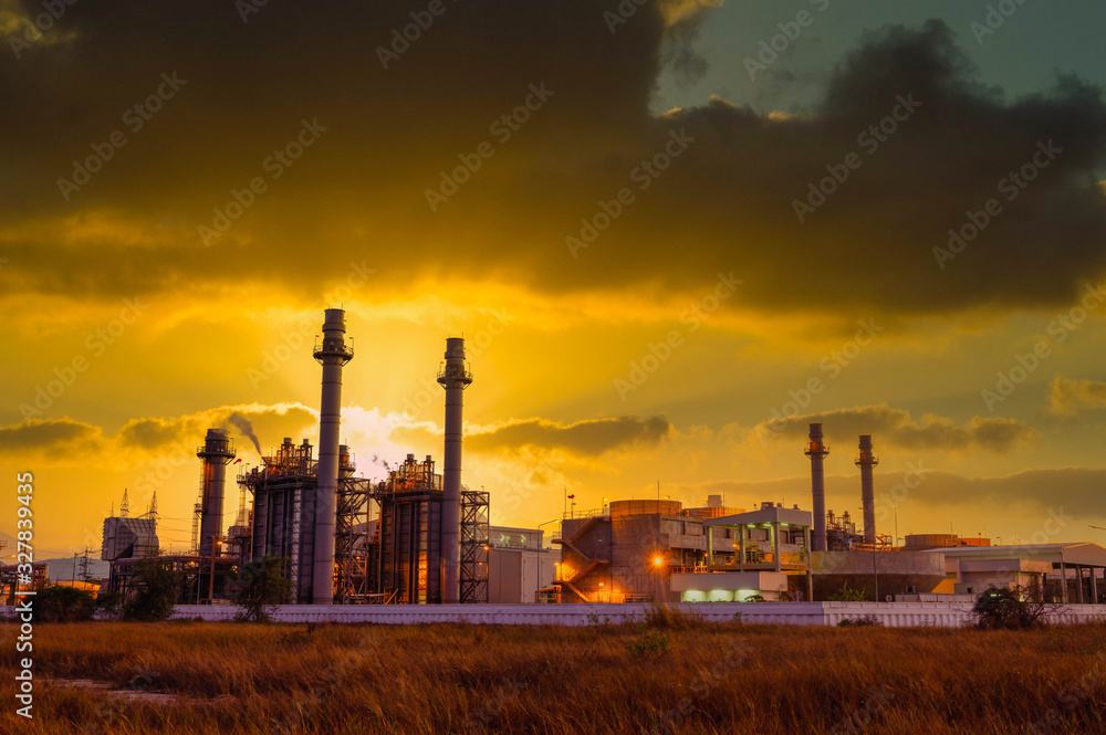 Natural gas combine cycle power plant and turbine generator in dusk with orange sky