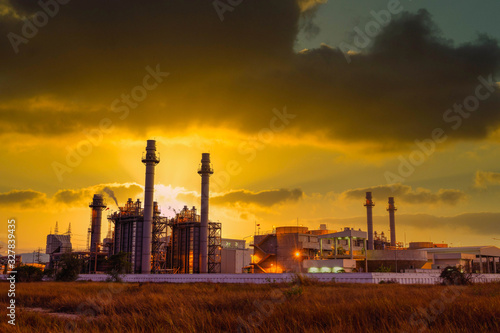 Natural gas combine cycle power plant and turbine generator in dusk with orange sky