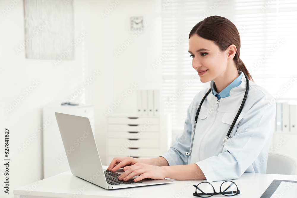 Young female doctor working with laptop at table in office Young female doctor working with laptop at table in office