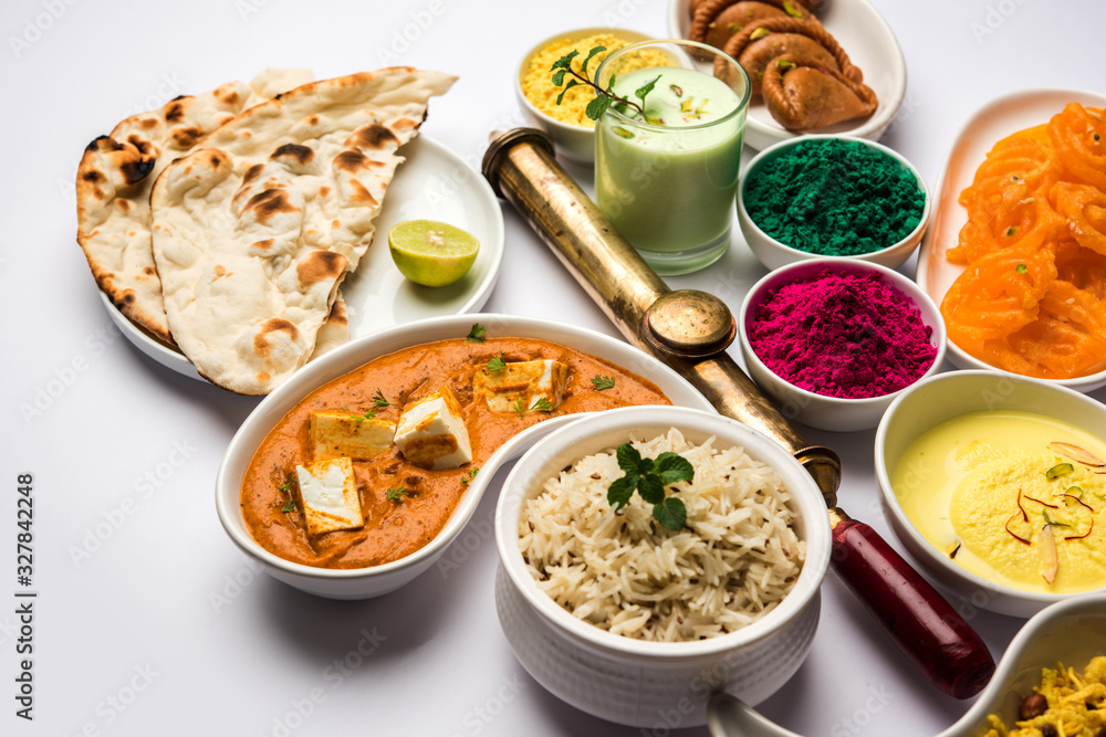 Happy Holy concept showing Indian assorted lunch food like chicken, paneer butter masala, naan, jeera rice, black chana fry, jalebi, fujiyama, thandai and Farsan with holi colours and pichkari Happy Holy concept showing Indian assorted lunch food like chicken, paneer butter masala, naan, jeera rice, black chana fry, jalebi, fujiyama, thandai and Farsan with holi colours and pichkari
