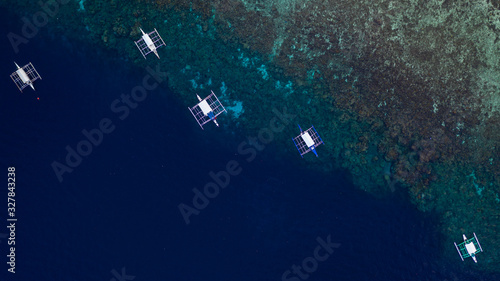 Aerial top down view of boat moving in open sea with clear and turquoise water on over coral reef, Boat left the tropical lagoon, Moalboal, Oslob, Cebu Island, Philippines.