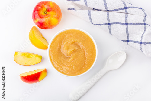 Fresh homemade applesauce. The concept of proper nutrition and healthy eating. Organic and vegetarian food. White bowl with fruit puree on fabric and cut apples on table. Baby food. Copy space for photo