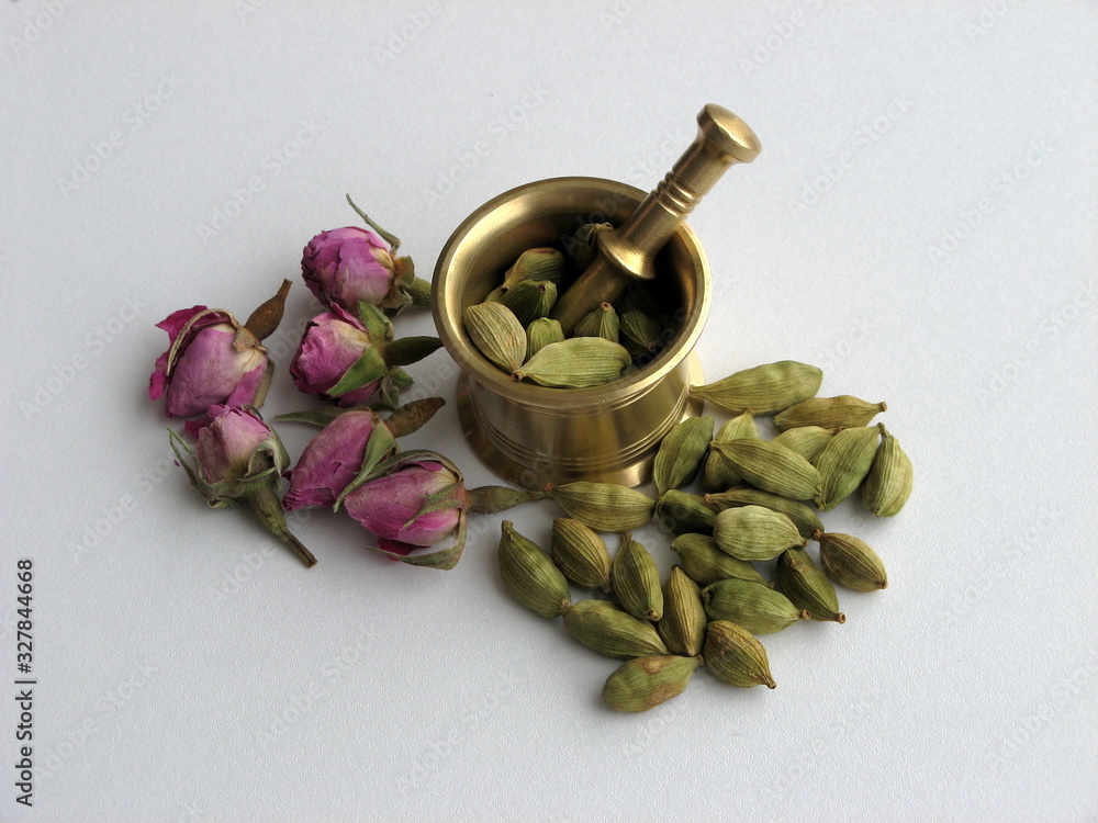 Green pods of cardamom spice in brass mortar on white background. Aromatic spice. Flower decoration. Close up. Green pods of cardamom spice in brass mortar on white background. Aromatic spice. Flower decoration. Close up.