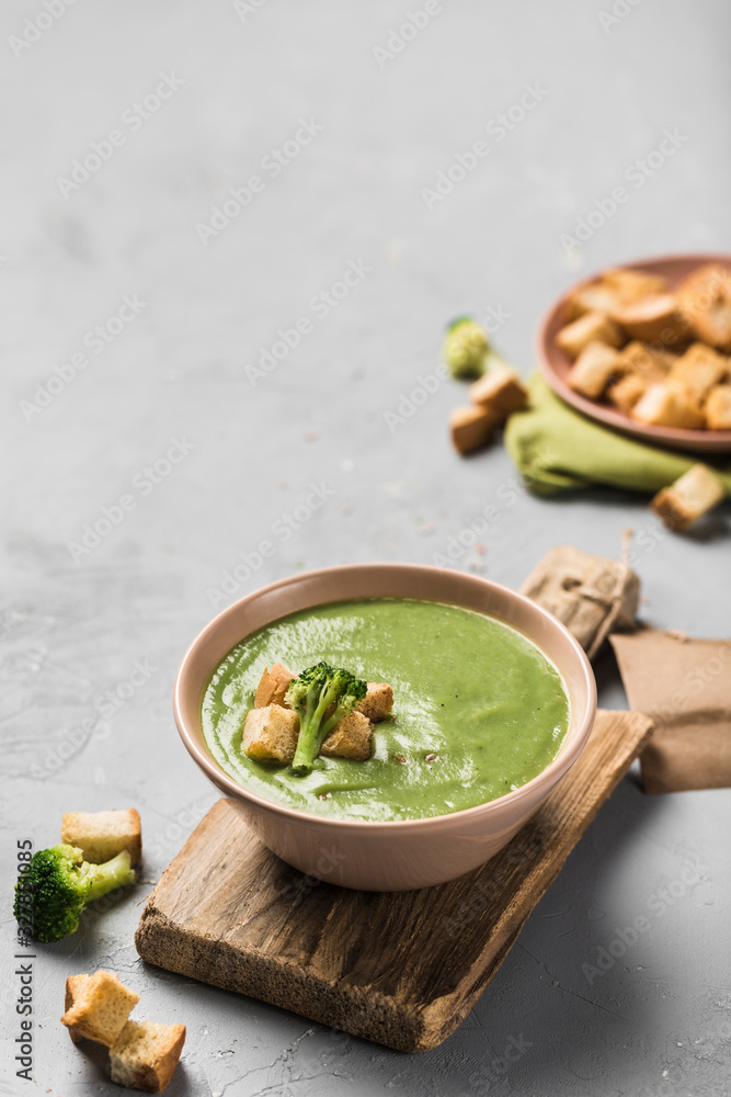 Cream broccoli soup with croutons in a plate on a wooden Board on a light gray background. Concept of healthy nutrition. Cream broccoli soup with croutons in a plate on a wooden Board on a light gray background. Concept of healthy nutrition.