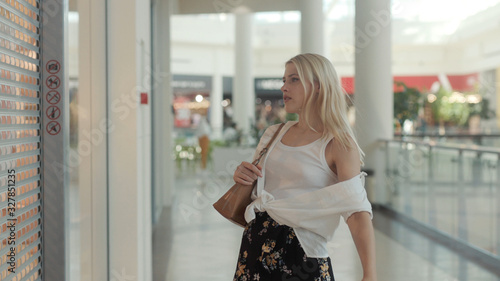Beautiful young blonde woman in white shirt shopping in a mall having a break. Lovely portrait of a sociable model girl.