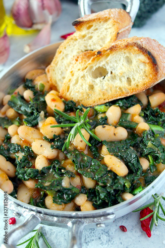 Stewed beans with black cabbage served with toasted bread. Vegetarian and vegan food. Top view with copy space.