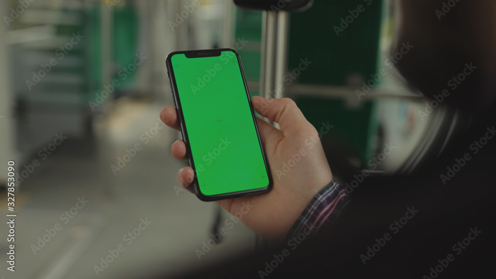 NEW YORK - May 19, 2019: Young man young hand uses holding a mobile telephone with a vertical green screen background tram chroma key smartphone technology touch message display close up NEW YORK - May 19, 2019: Young man young hand uses holding a mobile telephone with a vertical green screen background tram chroma key smartphone technology touch message display close up