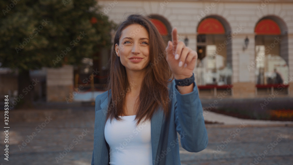 Portrait young woman uses smartwatch and virtual tablet with the latest advanced holographic technology on street outdoors internet mobile display telephone city portrait modern innovation slow motion