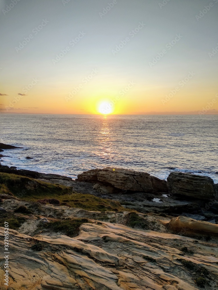 Obraz premium atardecer en el mar en costa con rocas 