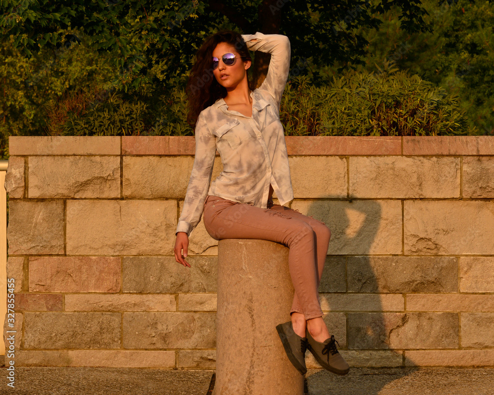 beautiful latina girl sitting on pedestal in front of rock wall beautiful latina girl sitting on pedestal in front of rock wall