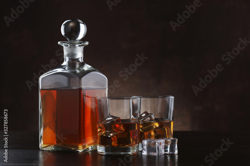 Bottle of whiskey with glasses on brown background