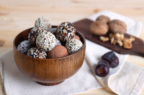 Raw protein energy balls in wooden bowl with walnuts and dates on light napkin. Energy balls ingredients, no baked. Selective focus, horizontal, close up