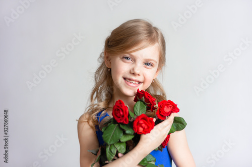 cute child 7-8 years old, mother's daughter, pretty little girl, girl with blond hair, with red roses gifted on women's day © Евгения Янцева