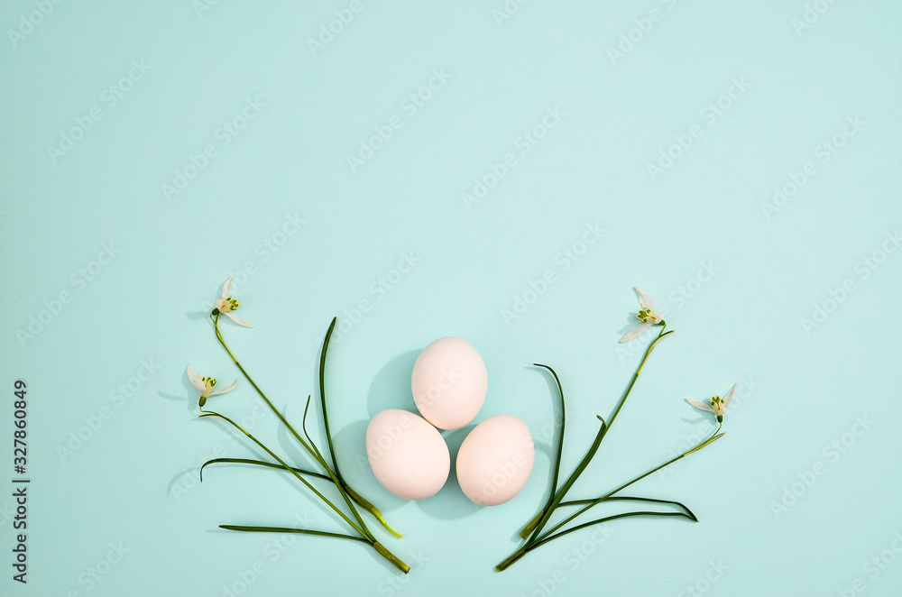 White eggs with green myrtle leaves pattern on mint color background. Spring and Easter holiday concept with copy space.