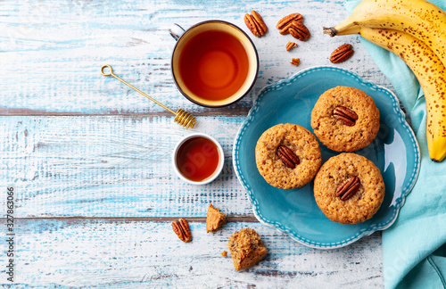 Pecan nut  banana muffins on a plate with cup of tea. Blue wooden background. Top view. Copy space.