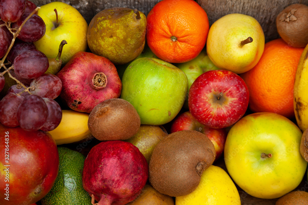 Fruit basket with different fruits. Vitamin set of a healthy diet. Fruit isolated on a gray background. Large set of fruits on a wooden kitchen table. Bananas, apples, pears, pomegranate, tangerine.