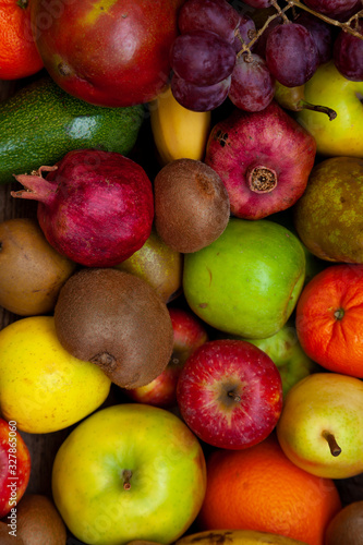 Fruit basket with different fruits. Vitamin set of a healthy diet. Fruit isolated on a gray background. Large set of fruits on a wooden kitchen table. Bananas  apples  pears  pomegranate  tangerine.