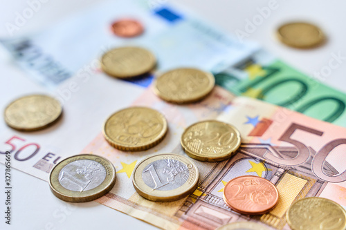 Calculation of expenses. Close up of one euro coin surrounded by different coins and 100 and 50 Euro banknotes