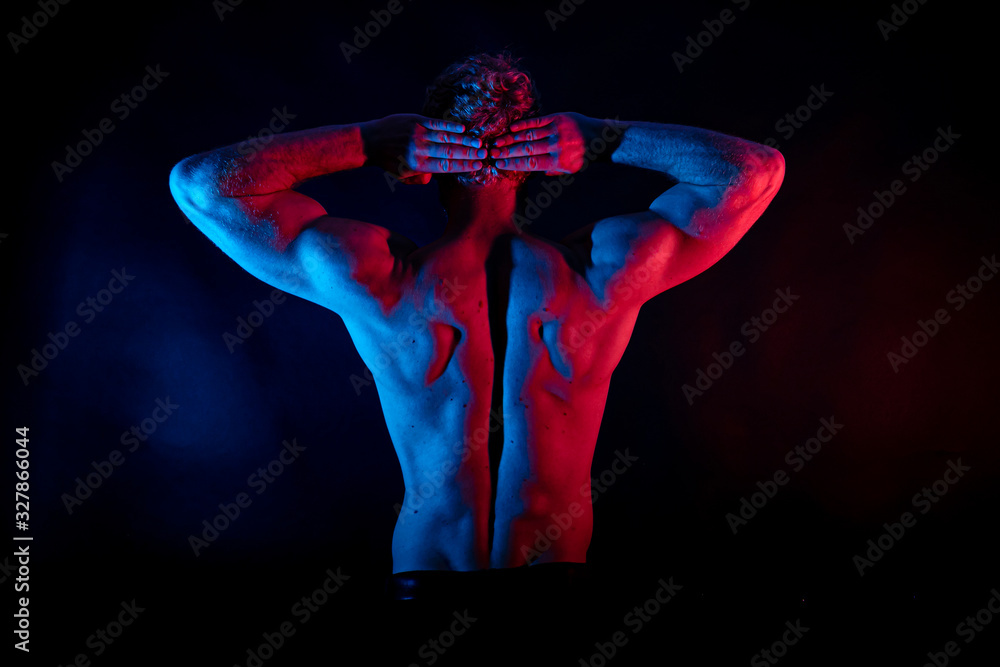 Obraz premium Male wrestler posing . studio black-white background, red and blue lights.