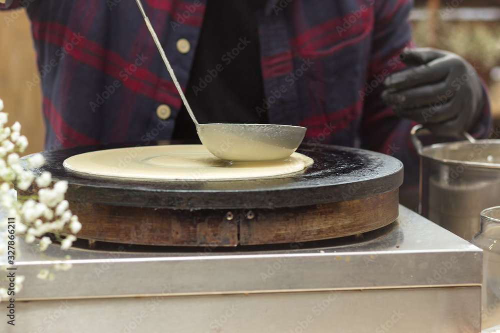 Close-up soup ladle with dough and oven. The dough is pouring on a crepe maker. A series of photos. Step-by-step photo recipe for pancakes. Close-up soup ladle with dough and oven. The dough is pouring on a crepe maker. A series of photos. Step-by-step photo recipe for pancakes.