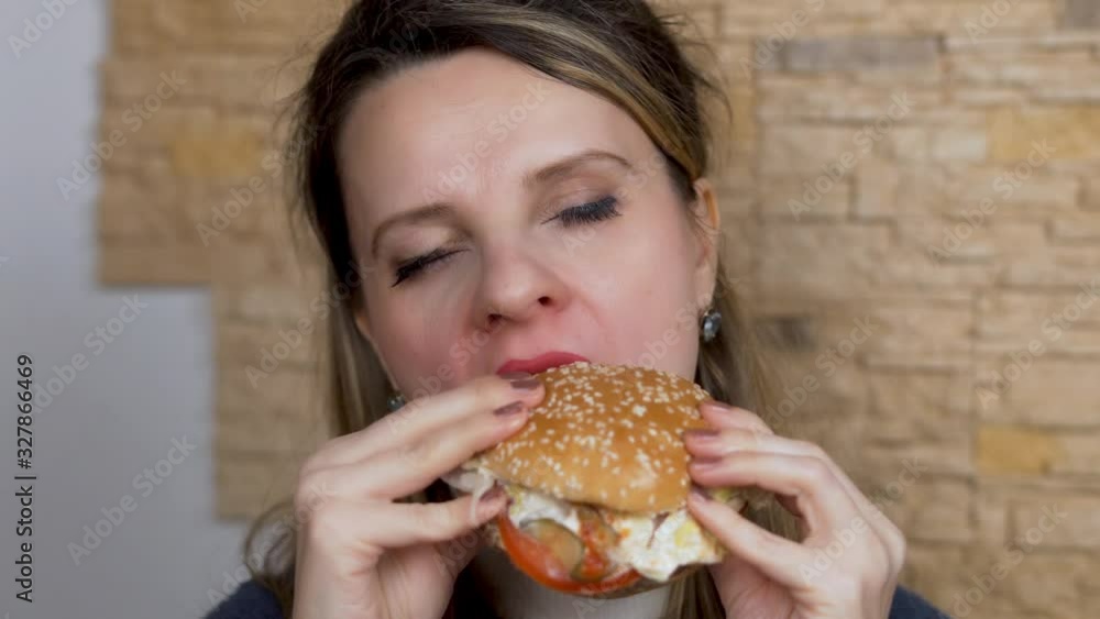 A Hungry Woman Greedily Eats a Burger Close-up. A Hungry Woman Greedily Eats a Burger Close-up.