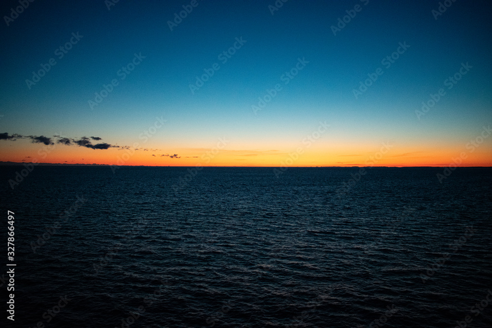 Obraz premium Sunset showing a golden or orange horizon with a dark blue sky.