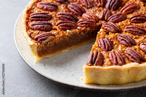 Pecan nut pie, tart on a plate. Grey background. Close up.