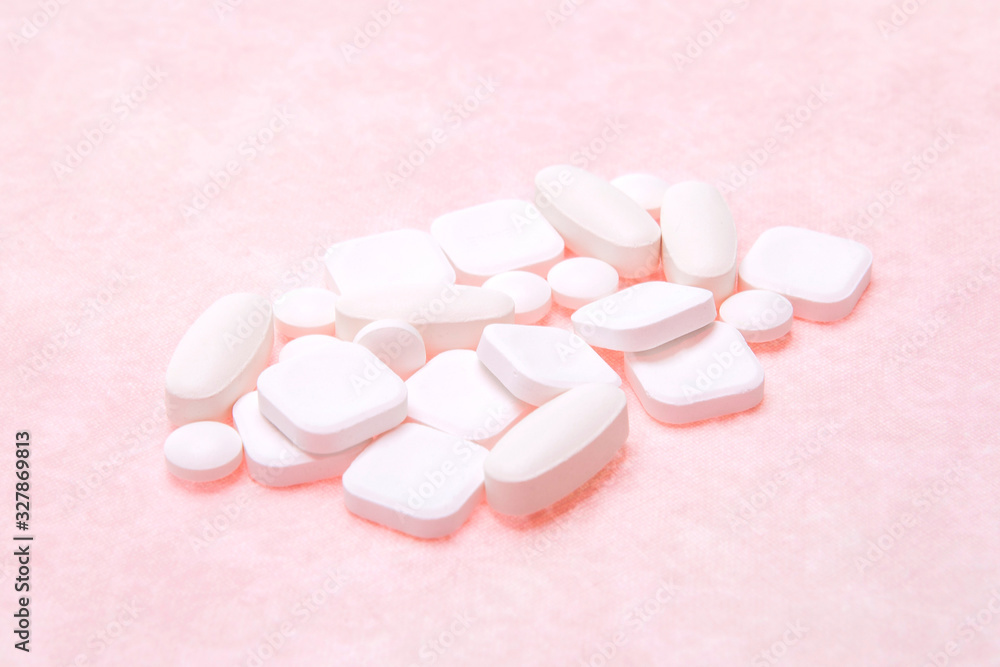A lot of pills of different shapes on a pink background A lot of pills of different shapes on a pink background
