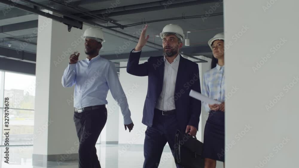 Tilt down shot of Caucasian architect making excursion for foreign business partners at new shopping center Tilt down shot of Caucasian architect making excursion for foreign business partners at new shopping center