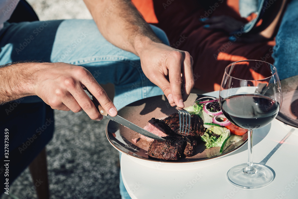 man eating meat with vegetables. Outdoors. Natural lighting