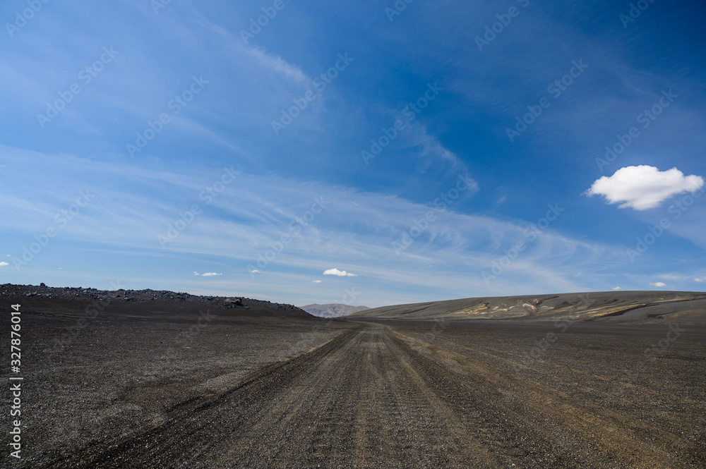 Gravel icelandic road in sunny day and blue sky