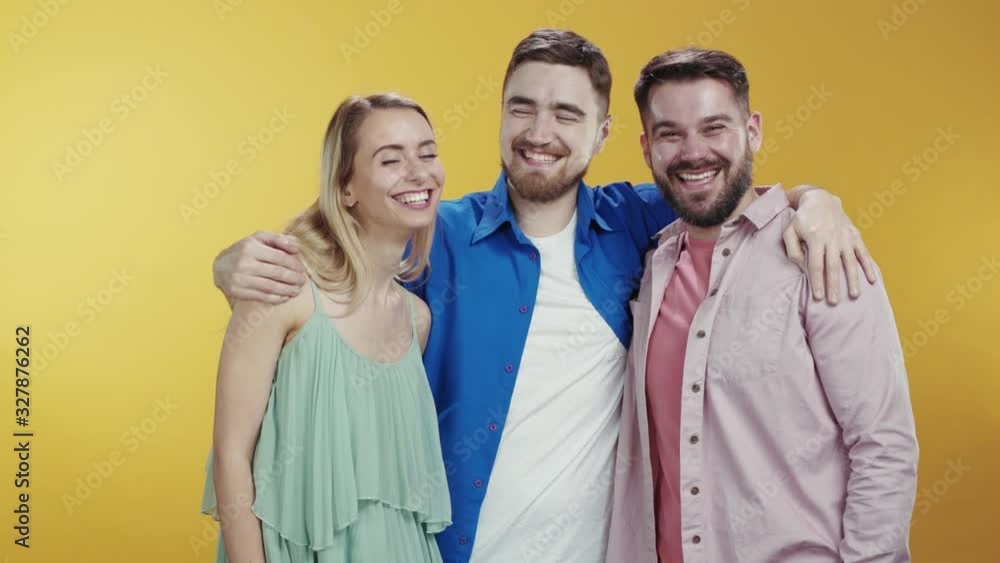 Happy fun guy appeares behind backs of his friends posing isolated on background. Family hipster portrait of three best friends laughing together at camera. Happy fun guy appeares behind backs of his friends posing isolated on background. Family hipster portrait of three best friends laughing together at camera.
