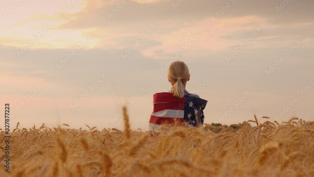 Farmer with usa flag on his shoulders stands in a vast field of ripe wheat Farmer with usa flag on his shoulders stands in a vast field of ripe wheat