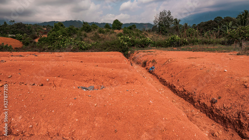 Red clay on the hill with tropical plants in rural Indonesia, pictured on a warm day in Padang, West Sumatra.