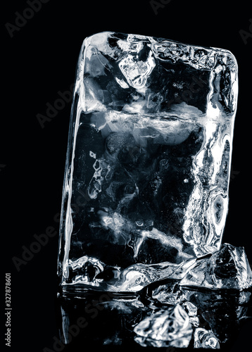 Crystal clear natural ice block on  black reflective surface. Clipping path included.