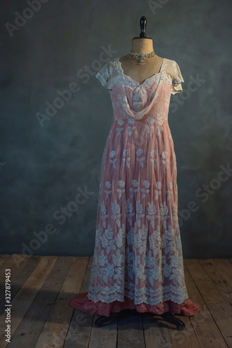 Pink victorian dress on vintage mannequin bust in empty room.