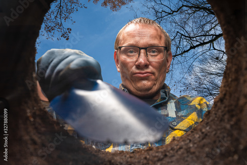 man with a shovel digs a hole bottom view