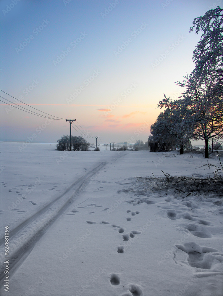 Obraz premium Snowy winter landscape at sunset.