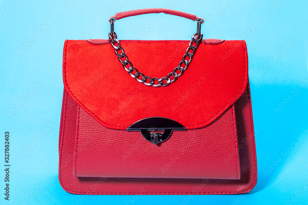 women's handbag in red leather and suede, object on a blue background. women's handbag in red leather and suede, object on a blue background.